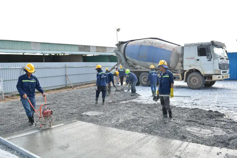 Workers pouring and leveling concrete from a mixer truck