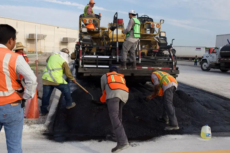 Road crew laying fresh asphalt with a paving machine